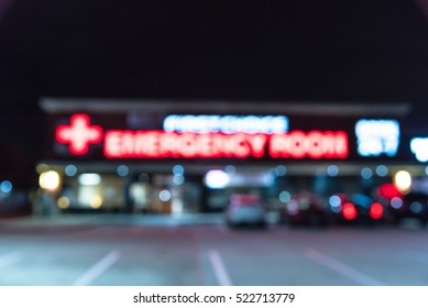 Blurred Image Exterior Emergency Room With Neon Led Sign Illuminated At Night In Houston, Texas, US. Facade Of Emergency Department With Neon Shining Signboard And Car Park. Healthcare Service Concept