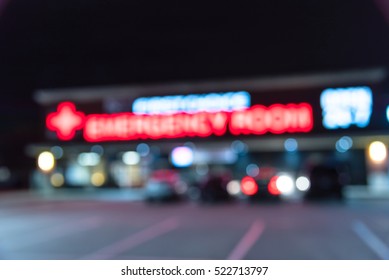 Blurred Image Exterior Emergency Room With Neon Led Sign Illuminated At Night In Houston, Texas, US. Facade Of Emergency Department With Neon Shining Signboard And Car Park. Healthcare Service Concept