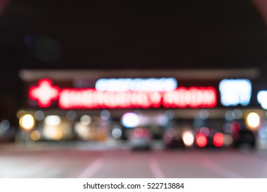 Blurred Image Exterior Emergency Room With Neon Led Sign Illuminated At Night In Houston, Texas, US. Facade Of Emergency Department With Neon Shining Signboard And Car Park. Healthcare Service Concept