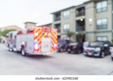 Blurred Image Fire Trucks, Firemen And Resident At Apartment Fire In Texas, US. Multi-floor Residential Building, Row Of Uncover Parked Car. Abstract Background Fire Incident Damage, Insurance Concept