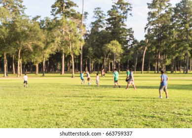 Blurred Image Group Of Latin America Kids Playing Football On Green Soccer Pitch Of The Park At Sunset With Warm Light In Humble, Texas. Urban Healthy Lifestyle Concept. Boys Kicking Football On Field