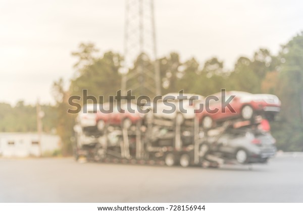 Blurred image huge car carrier truck of new\
cars for batch delivery to dealership. Full load trailer car\
transporter of new vehicles in transit  in Texas, USA. Automotive\
industry abstract\
background