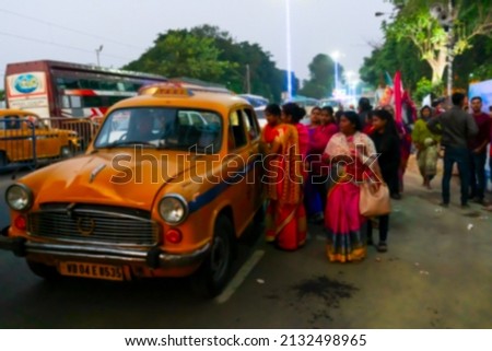Blurred image of Kolkata, West Bengal, India. Hindu female devotees negotiating fare with yellow taxi driver, at Gangasagar transit camp, Babughat, Kolkata.