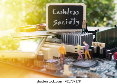Blurred image of label wording Cashless society and  miniature mini  figures standing on computer mainboard. Integrated Circuit. the concept of cashless society. blur mobile phone  background