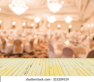 Blurred Image Of Large Dining Table Set For Wedding, Dinner Or Festival Event With Beautiful Lights Decoration Inside Large Hall With People.