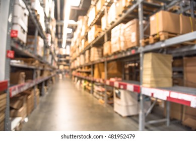 Blurred image of large furniture warehouse with row of aisles and bins from floor to ceiling. Defocused background industrial storehouse interior aisle. Inventory, wholesale, logistic, export concept.