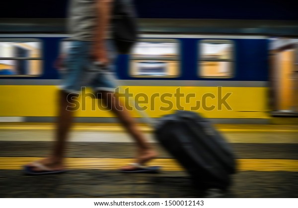 Blurred image. man\
with luggage waving at train station on wagon background. no face.\
railway station. 