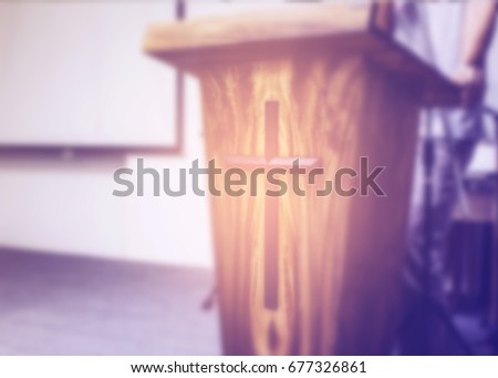 Blurred image of a man  making speech from behind the pulpit with Jesus cross in church service, can  be used for christian background