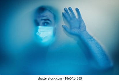 A blurred image of a man wearing a medical mask on his face. Through a matte face silhouette. COVID-19 self-isolation and social distance concept