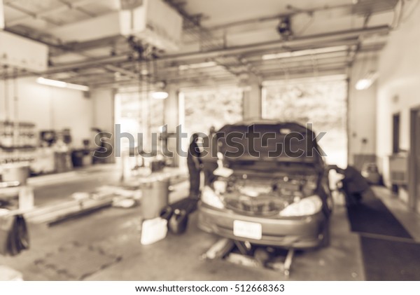 Blurred image mechanic changing oil of car at auto\
shop in Little Rock, Arkansas, US. Defocused background interior of\
car oil change service station. Working technician at auto repair.\
Vintage filter