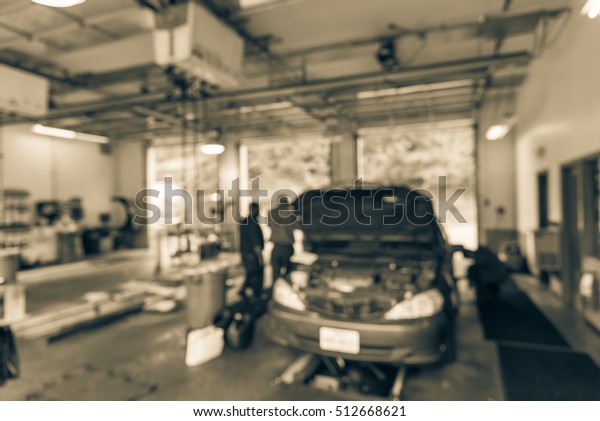Blurred image mechanic changing oil of car at auto\
shop in Little Rock, Arkansas, US. Defocused background interior of\
car oil change service station. Working technician at auto repair.\
Vintage filter