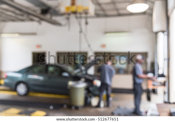 Blurred image mechanic changing oil of car at\
auto shop in Little Rock, Arkansas, US. Defocused background\
interior of modern oil change service station. Working technician\
at auto repair concept.