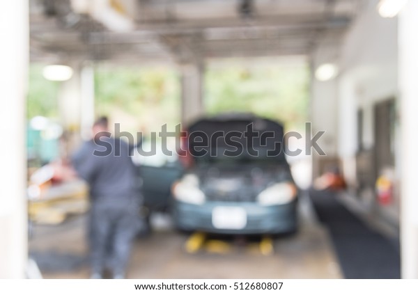 Blurred image mechanic changing oil of car at\
auto shop in Little Rock, Arkansas, US. Defocused background\
interior of modern oil change service station. Working technician\
at auto repair concept.