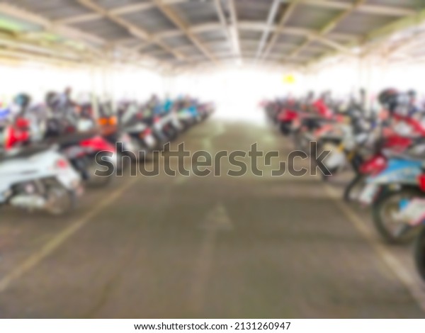 Blurred image of a motorcycle parked in a shopping\
mall.  Supermarket with lots of motorbikes parked.  Parked in an\
orderly row in a long\
line.