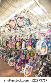 Blurred Image Multiple Rows Of Kid Bikes Hanging On Rack At Department Store In Humble, Texas, US. Various Bright Color Bicycles For Active Kids In Bike Shop. Healthy Lifestyle Concept Background.