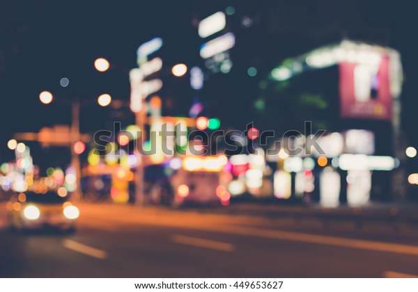 Blurred image of night city.\
City at night. Shop signs with different colors and cars in\
motion.