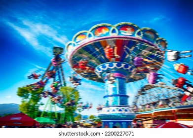 Blurred image of people enjoying vintage fair rides at nostalgic amusement park