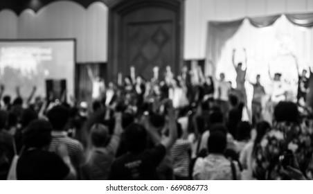 Blurred image of people raising hands in concert in black and white tone for religion background