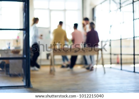 Blurred image, people silhouette collaborating in office interior. Defocused space for your information, teamwork process. Group of coworkers discussing ideas. Colleagues having informal work meeting