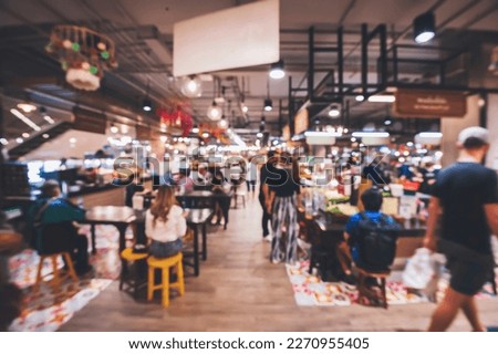 blurred image of people sitting and eating in the food court