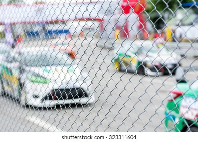 Blurred Image Of Racing Car On Track View From Behind Fence 