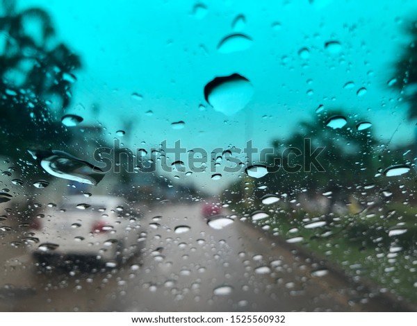 Blurred image, raindrop on car\
windshield,colorful bokeh with street light.Driving car in heavy\
rain storm.Traffic in the city on a rainy\
day.