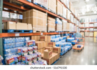 Blurred image row of aisles, bins and shelves from floor to ceiling with flatbed cart in large warehouse. Defocused background industrial distribution storehouse interior aisle, hypermarket, wholesale