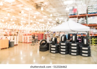 Blurred image rows of brand new tires for sale at booth in wholesale store. Defocused background of industrial warehouse interior aisle. inventory, hypermarket, wholesale, logistic and export concept.