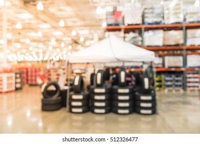 Blurred image rows of brand new tires for sale at booth in wholesale store. Defocused background of industrial warehouse interior aisle. inventory, hypermarket, wholesale, logistic and export concept.