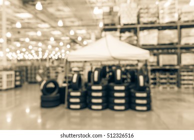 Blurred image rows of brand new tires for sale at booth in wholesale store. Defocused background of interior aisle for inventory, hypermarket, wholesale, logistic and export concept. Vintage filter.