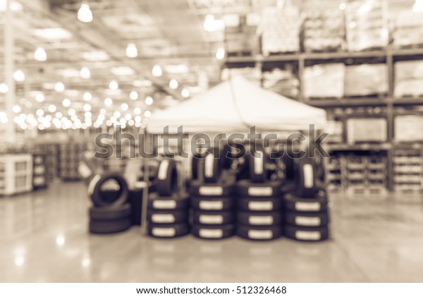 Blurred image rows of brand new tires for sale at
booth in wholesale store. Defocused background of interior aisle
for inventory, hypermarket, wholesale, logistic and export concept.
Vintage filter.