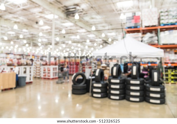 Blurred image rows of brand new tires for sale\
at booth in wholesale store. Defocused background of industrial\
warehouse interior aisle. inventory, hypermarket, wholesale,\
logistic and export\
concept.