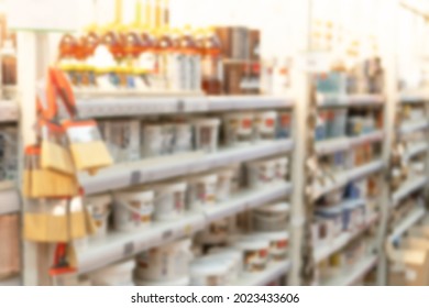 Blurred Image Of Shelves With Interior Paints, Varnish, Brushes In Store Of Building Materials As Shopping And Trading Background.