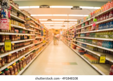 Blurred Image Of Supermarket Aisle And Shelves. Wide Perspective View Of Empty Supermarket Aisle, Defocused Blurry Background With Bokeh Light In Store. Business Concept.