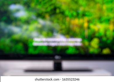 Blurred image of a television screen with a green nature documentary and subtitles