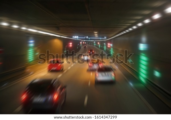 blurred image of  tunnel  with lights, defocused\
cars and speed limit signs. Signs in dark tunnel by tilt-shift\
speed limit and motion