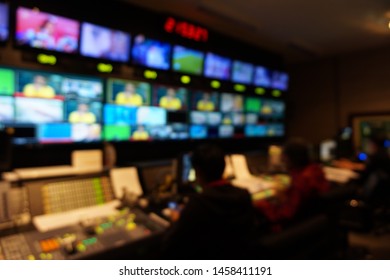 Blurred image of the TV production team in the broadcast control room, which includes video switch and audio mixer, control broadcasts in recording studio.