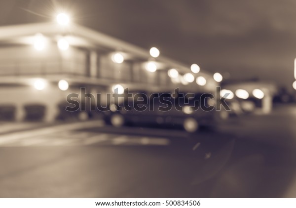 Blurred image of two story motel with parking lot\
in foreground at blue hour in Hope, Arkansas, US. Generic budget\
motel in suburban roadside location with row parked car next to\
room. Vintage filter.