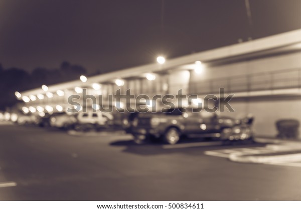 Blurred image of two story motel with parking lot\
in foreground at blue hour in Hope, Arkansas, US. Generic budget\
motel in suburban roadside location with row parked car next to\
room. Vintage filter.