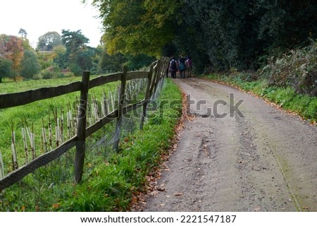 Blurred image of walkers on country lane alongside wooden fence