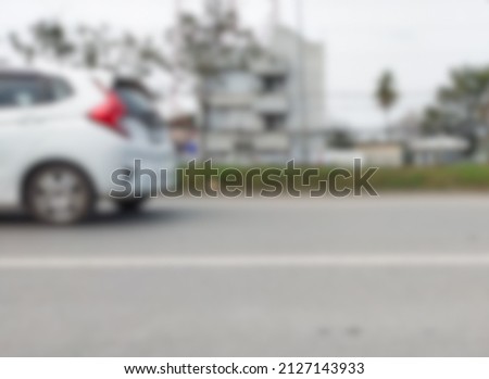 Blurred image of a white sedan driving on the road.