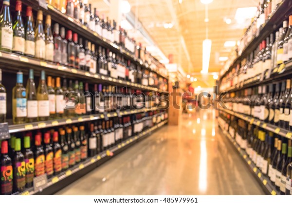 Blurred image\
of wine shelves display in supermarket. Defocused  Rows of Wine\
Liquor bottles on the store shelf. Alcoholic beverage abstract\
background. Alcohol drink market\
concept.