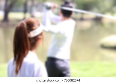 Blurred Image Of Young Businessman And Caddy Playing Golf In The Lawn In The City Center. 