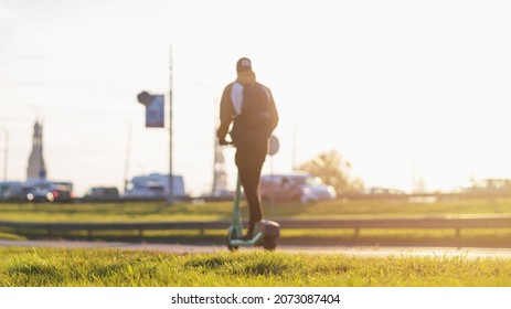 Blurred Image Of Young Man Riding An E-scooter In City Traffic. Electric Scooter New Way City Mobility. Green Transportation. Sustainable Climate-neutral Cities Goals. 