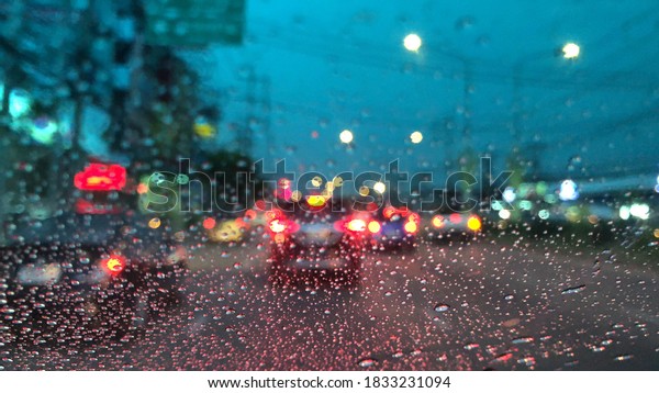 Blurred image,colorful bokeh with\
street light,Rain falling on car windshield, drive car on the road\
in city at heavy rain storm,selective\
focus.