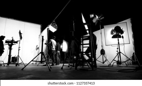 Blurred images of behind the scenes TV commercial movie film or video shooting production which crew team and camera man setting up green screen for chroma key technique in big studio.