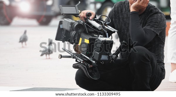Blurred images of high definition video camera and lens
on steady equipment support such as gimbal steady or stabilized
shoulder rig and pan tilt shift head tripod for handheld filming
moving object. 