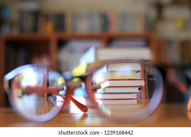 Blurred images of stacked books viewed from the reflection of the glasses