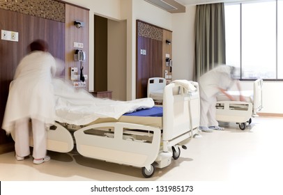 Blurred Images Of Staff Members Changing Hospital Bed Sheets In Modern Equipped Room