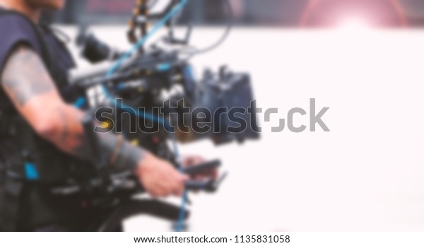 Blurred images of video camera and lens on steady\
equipment support such as gimbal steady or stabilized shoulder rig\
and pan tilt shift head tripod for handheld filming a fast moving\
object in tvc